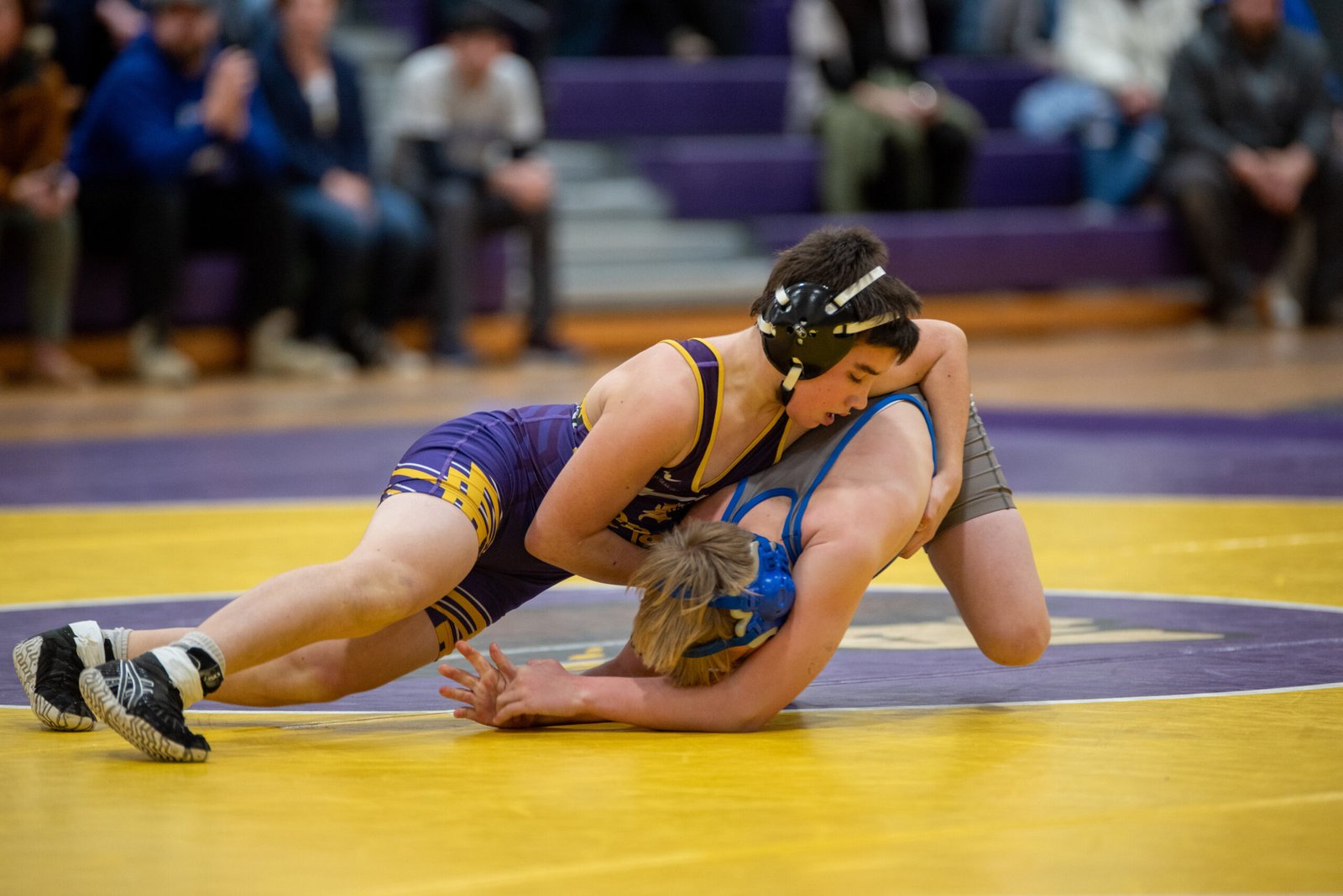 Ephrata Middle School wrestling action shot during a takedown on the mat at an indoor match with a blurred crowd in the background in Ephrata, PA.