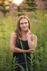 High school senior standing in tall wildflowers at golden hour at Middle Creek Wildlife Preserve in Stevens, PA.