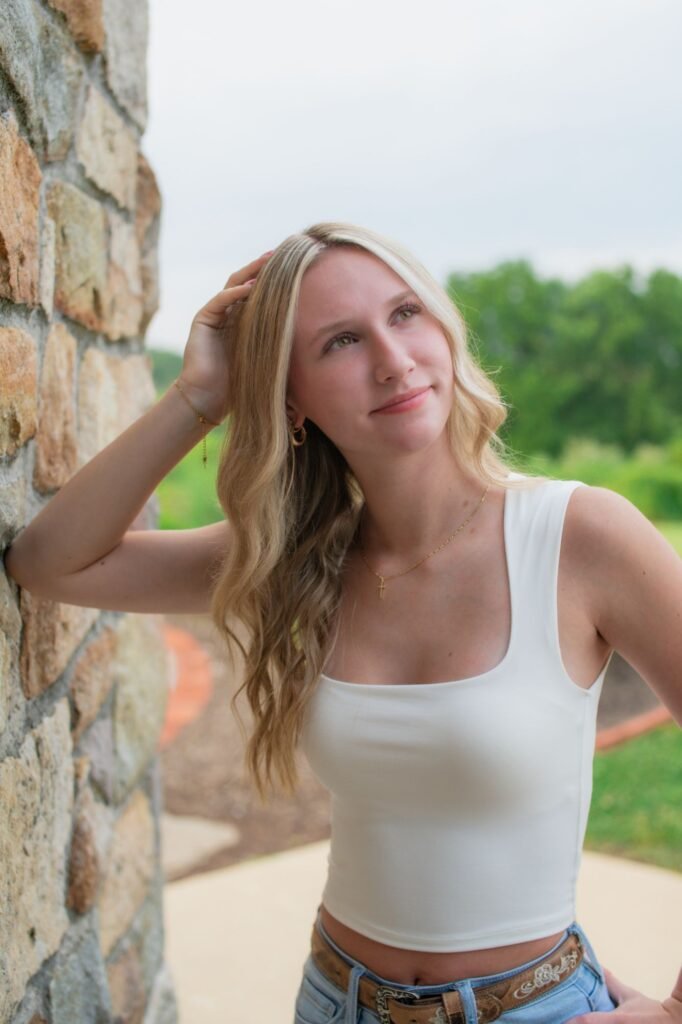 Natural light senior portrait of a woman leaning against a wall in Ephrata PA