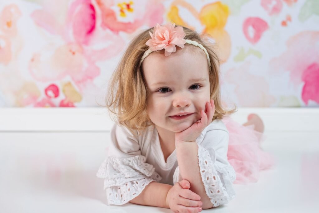 Toddler girl laying down smiling at camera for childrens portraits